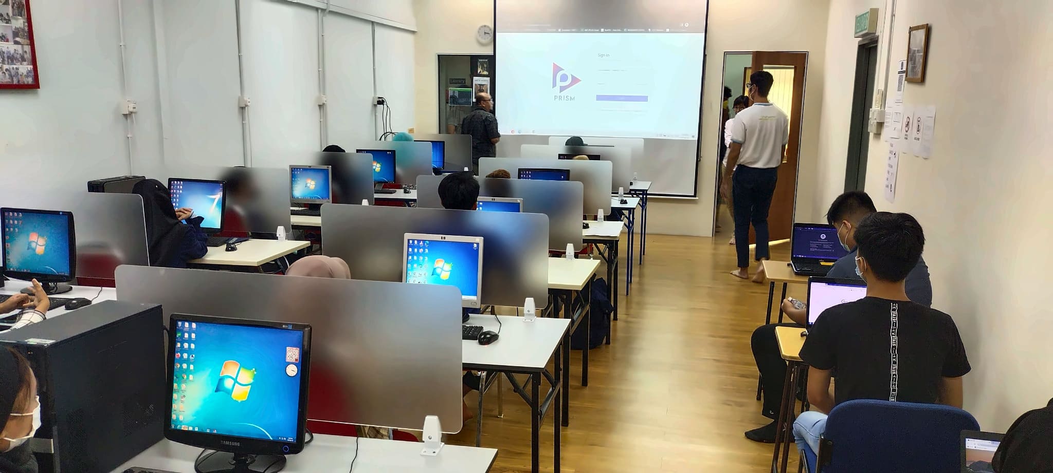 Computer lab training session with the PRISM system sign-in screen projected at the front
