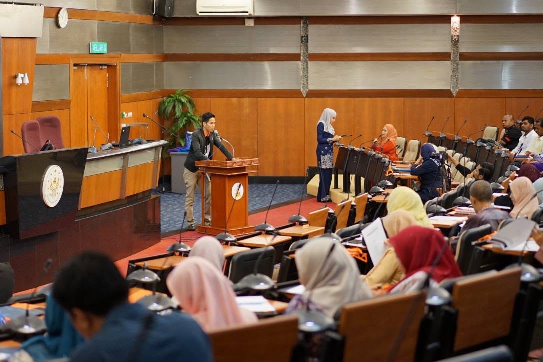 Presenter delivering a security posture assessment briefing to participants in a conference hall